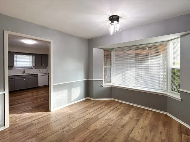 a view of a kitchen and an empty room with wooden floor and a window
