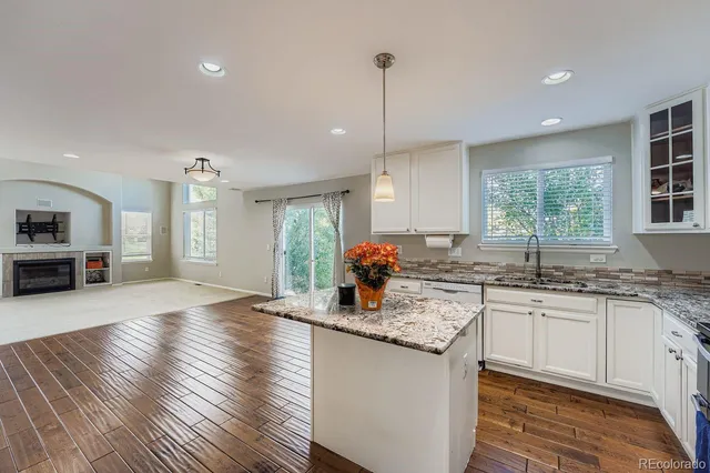 a kitchen with granite countertop a stove a sink dishwasher a refrigerator and wooden floor