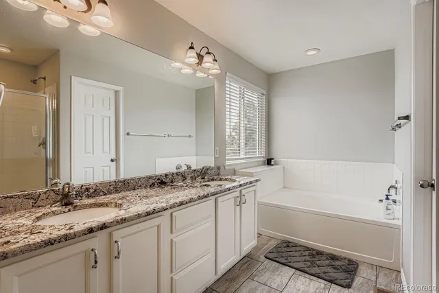 a bathroom with a granite countertop sink a mirror and a bathtub with shower