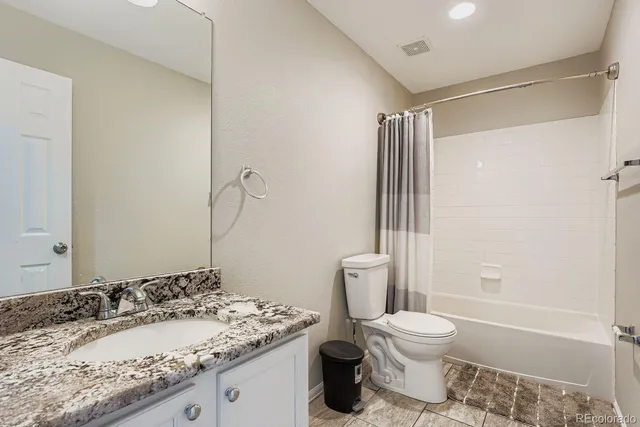 a bathroom with a granite countertop sink toilet and shower