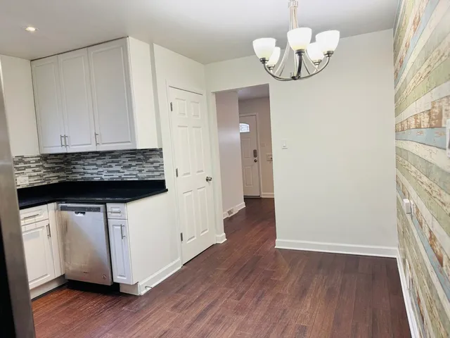 a kitchen with stainless steel appliances granite countertop wooden floors and chandelier