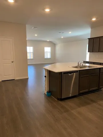 a kitchen with stainless steel appliances granite countertop a sink a stove top oven and wooden floor