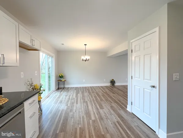 a view of a sink and an empty room with wooden floor