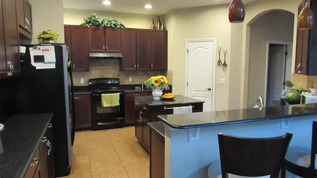 a kitchen with granite countertop a stove refrigerator and microwave