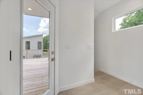 a view of a hallway with wooden floor and a bathroom