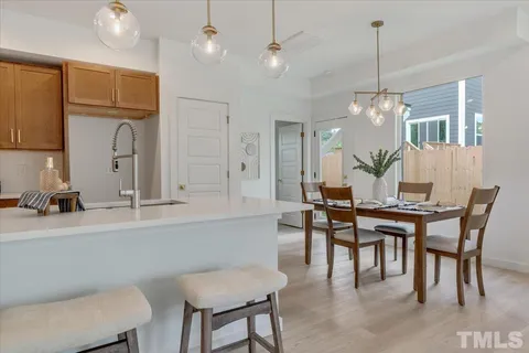 a dining room with wooden floor a chandelier a wooden table and chairs