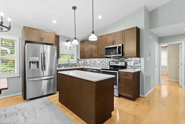 a kitchen with kitchen island a counter top space stainless steel appliances and wooden floor