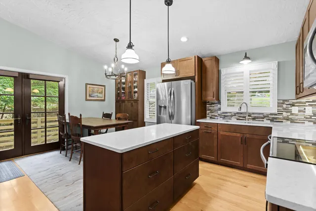 a large kitchen with kitchen island a stove a sink a center island and a wooden floor