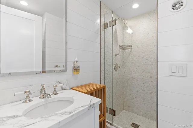 a bathroom with a sink shower and a mirror