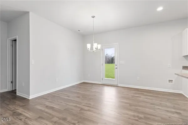 an empty room with wooden floor fireplace and windows