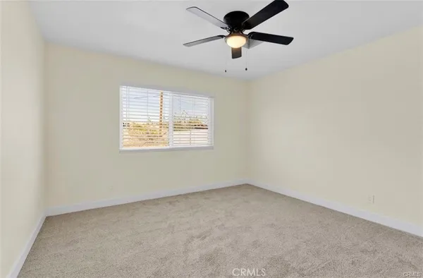 an empty room with a window and a fan
