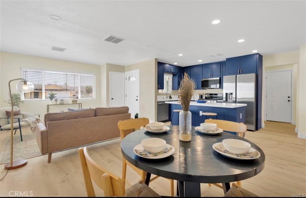 351 Armory Road Barstow, CA 92311 - Photo 6 of 31 a kitchen with stainless steel appliances wooden floor dining table and chairs