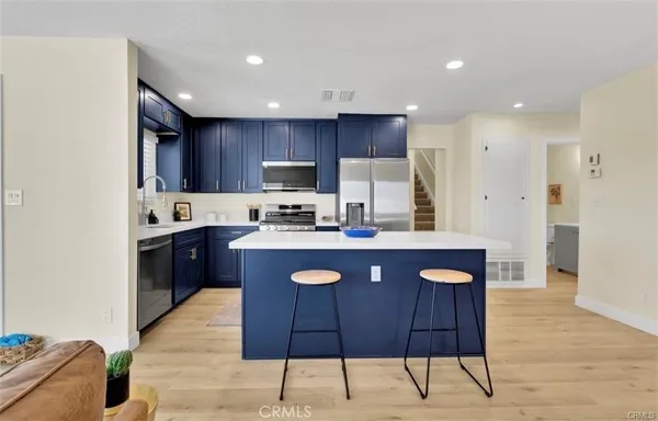 a kitchen with kitchen island granite countertop wooden floors appliances and cabinets