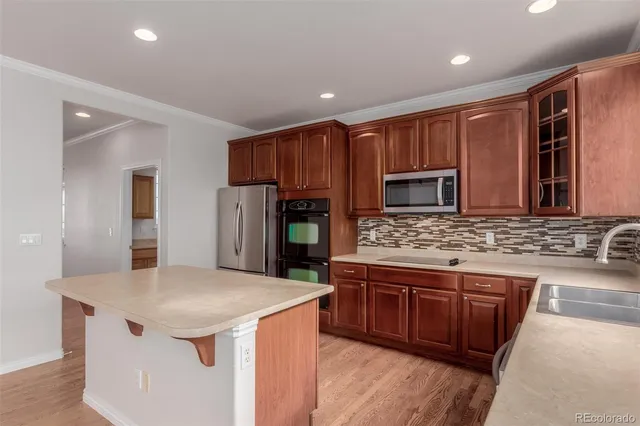 a kitchen with stainless steel appliances kitchen island granite countertop a stove refrigerator and cabinets
