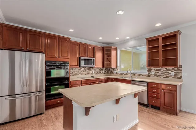 a kitchen with stainless steel appliances granite countertop a refrigerator a sink dishwasher a stove and a refrigerator