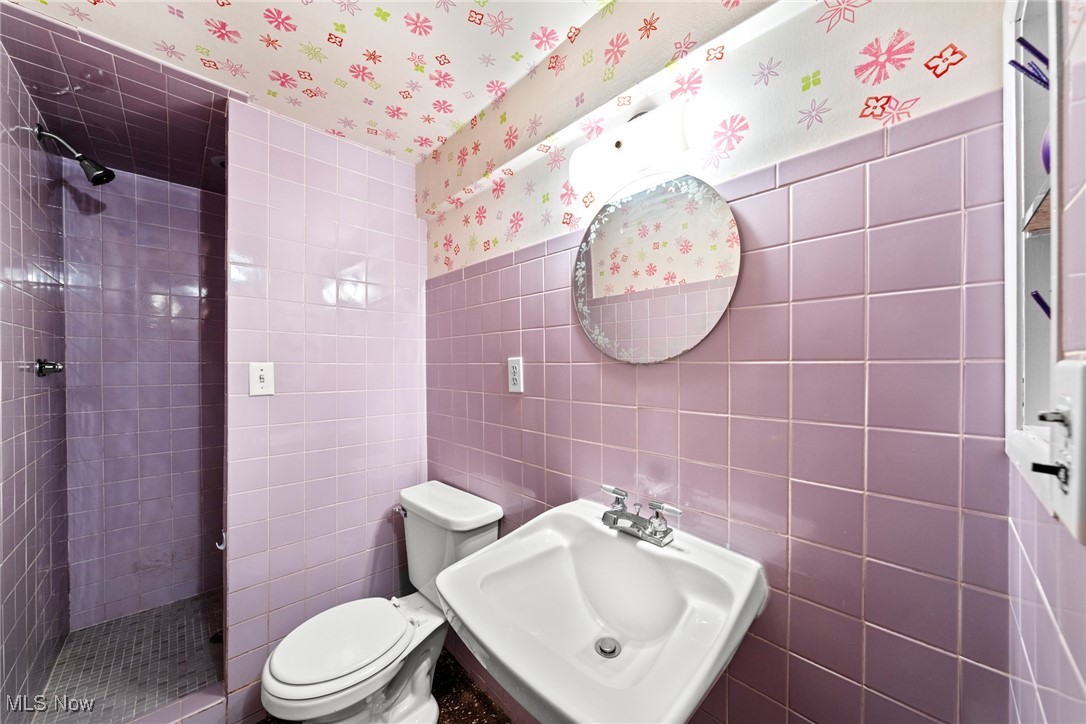 29776 Arthur Road Wickliffe, OH 44092 - Photo 38 of 49 Bathroom with wallpapered walls, a tile shower, tile walls, and a wainscoted wall