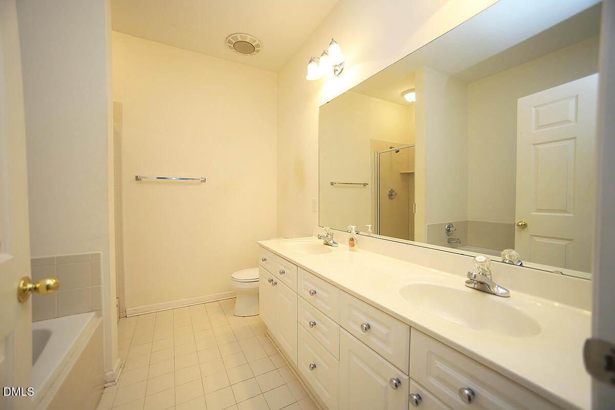 3161 Hemlock Forest Circle, Unit 101 Raleigh, NC 27612 - Photo 15 of 21 a spacious bathroom with a double vanity sink toilet mirror and bathtub