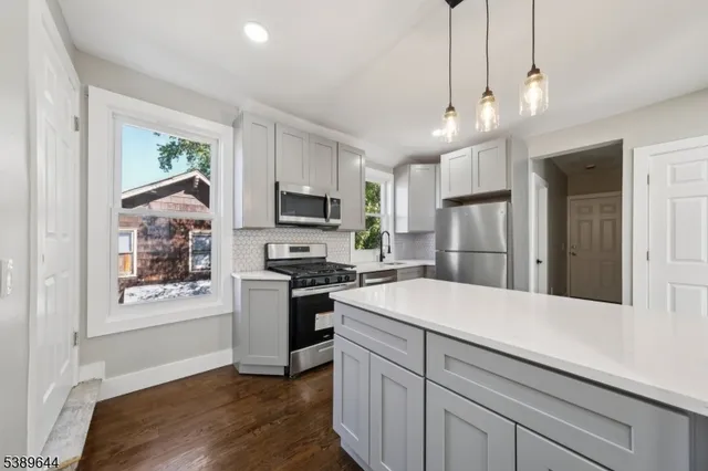 a kitchen with a refrigerator a sink and wooden floor