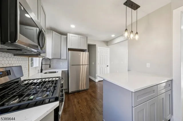 a kitchen with stainless steel appliances a sink a stove a refrigerator cabinets and a window