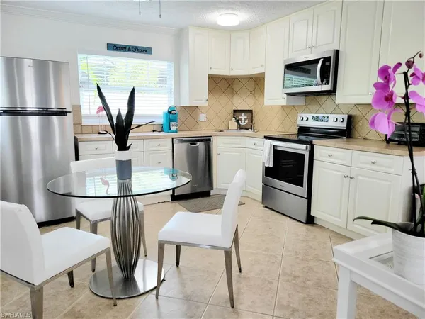 a kitchen with stainless steel appliances granite countertop a refrigerator a stove a sink a dining table and chairs