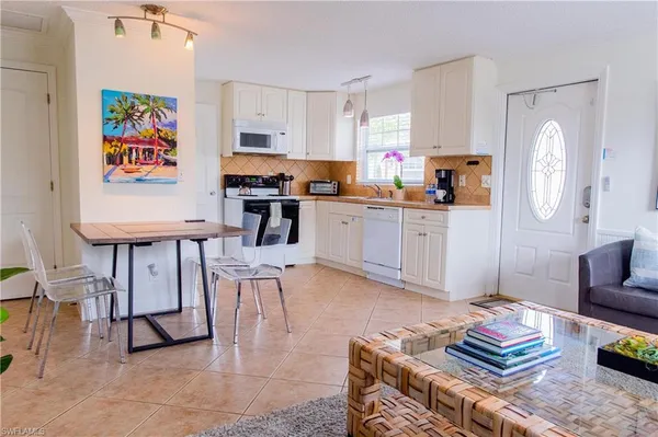 a kitchen with stainless steel appliances kitchen island granite countertop a stove top oven a sink a dining table and chairs with wooden floor