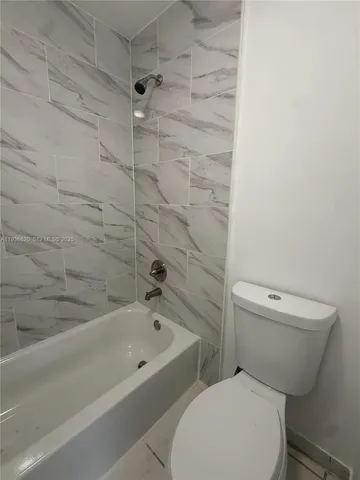 a white toilet sitting next to a bath tub and a shower