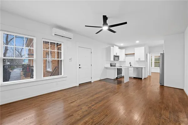 a view of a living room with wooden floor and windows