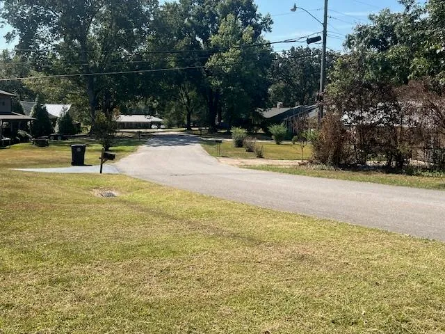 a view of swimming pool with lawn chairs and large trees