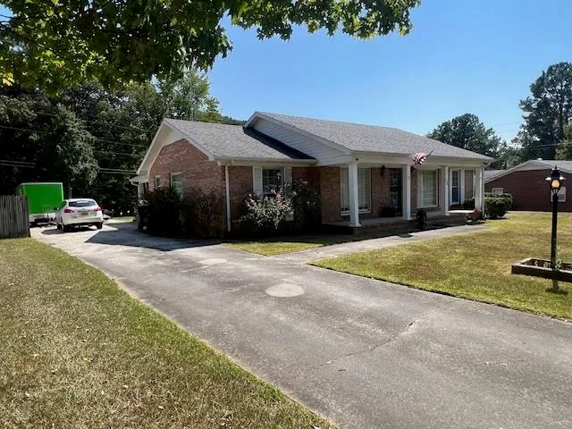 a front view of a house with a garden and trees