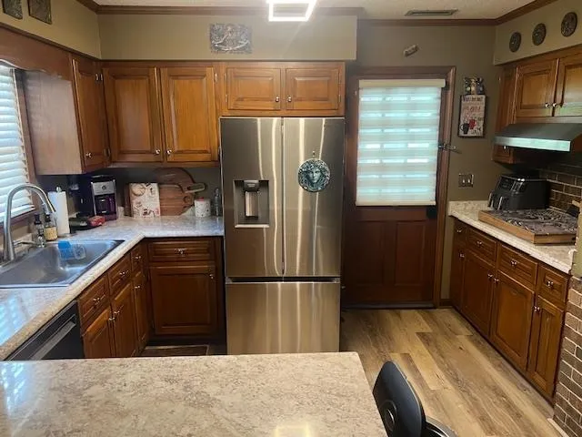 a kitchen with granite countertop a refrigerator a sink a stove and cabinets