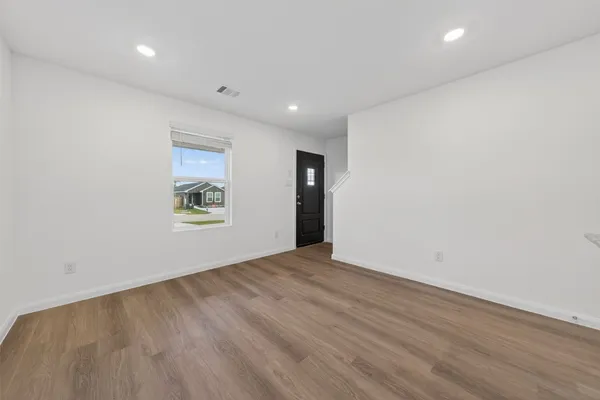 an empty room with wooden floor and windows