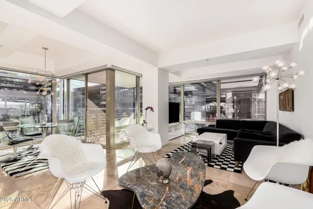 a living room with furniture large windows and wooden floor