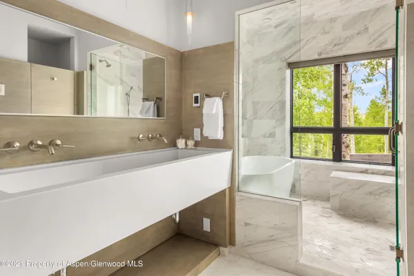 a bathroom with a tub a sink and a large mirror