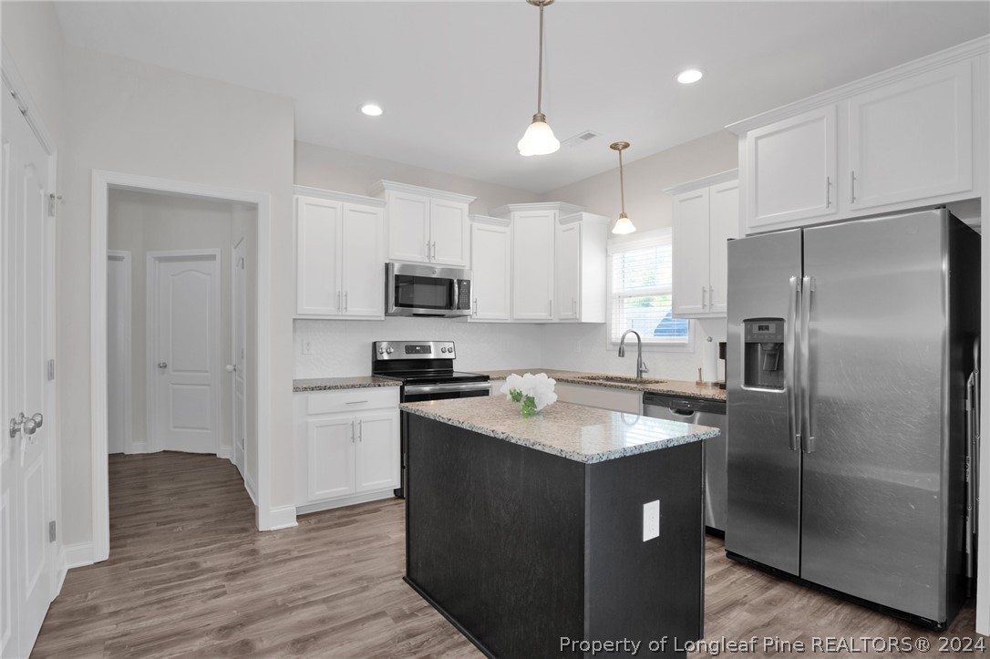 9670 East Reeves Bridge Road Linden, NC 28356 - Photo 11 of 35 a kitchen with kitchen island granite countertop a sink stainless steel appliances and white cabinets