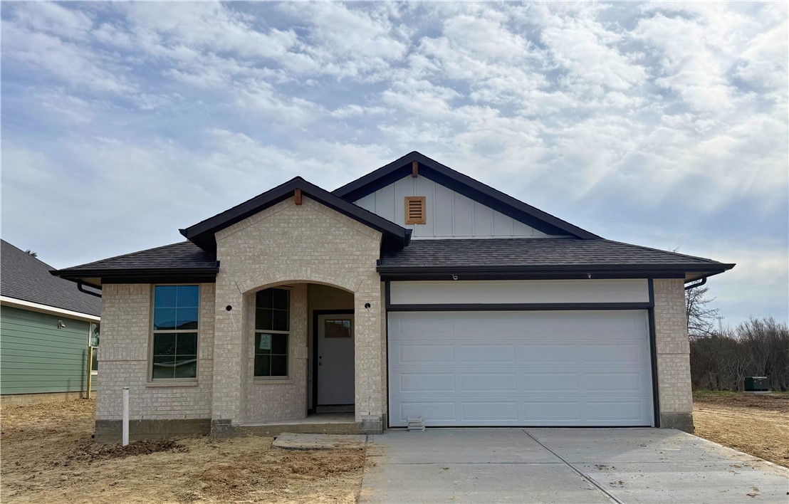 View of front of home featuring board and batten siding, brick siding, an attached garage, driveway, and a shingled roof