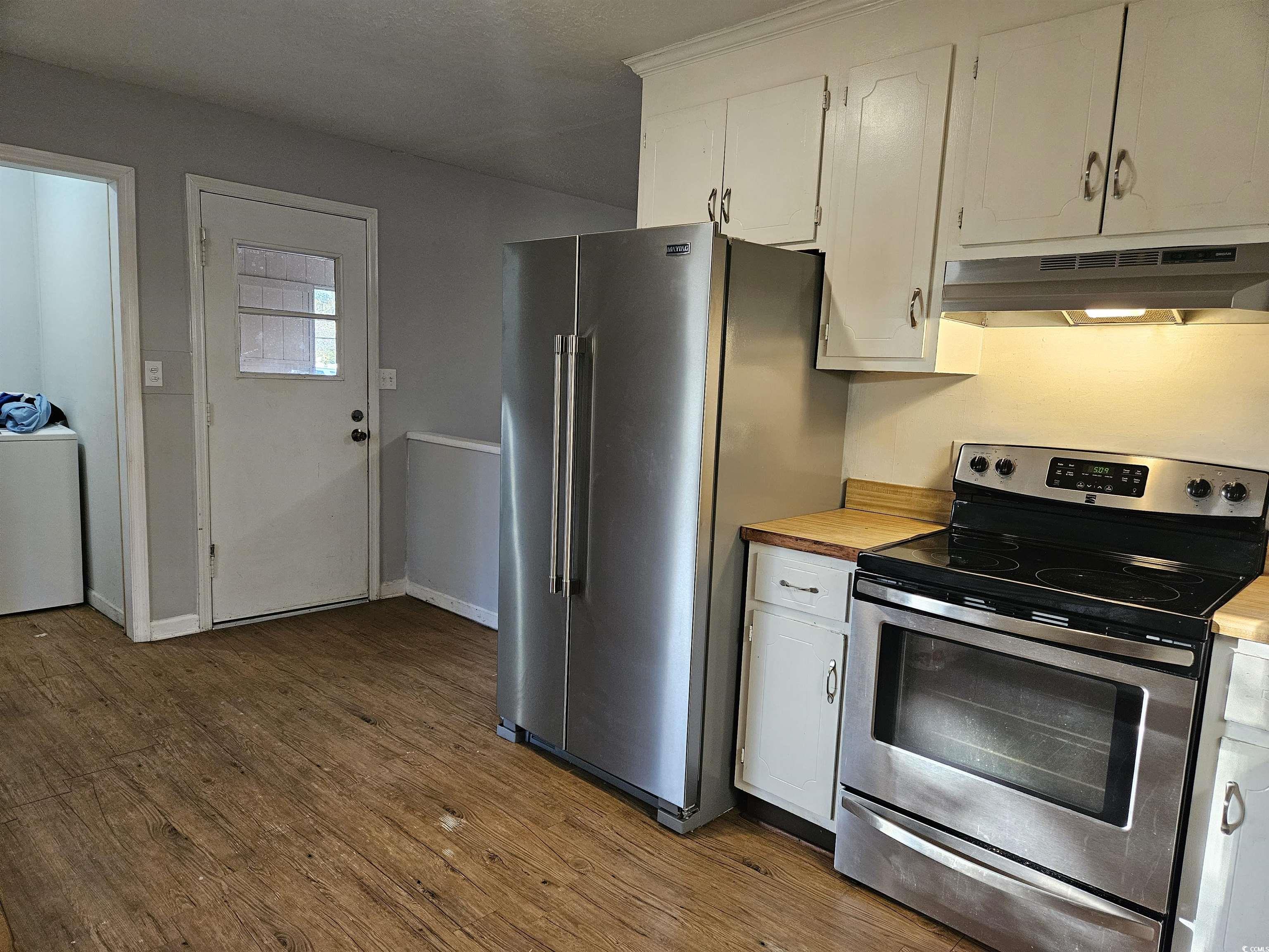 602 Jefferson Way Conway, SC 29526 - Photo 13 of 20 Kitchen with appliances with stainless steel finishes, white cabinetry, dark wood-style flooring, under cabinet range hood, and washer / clothes dryer