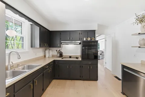 a kitchen with kitchen island granite countertop a sink dishwasher stove and refrigerator with wooden floor