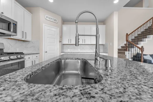 a kitchen with kitchen island a stove a sink and white cabinets