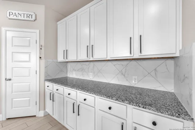 a kitchen with granite countertop white cabinets and sink