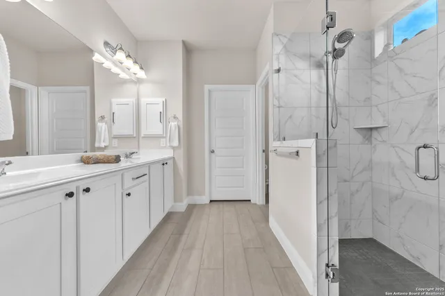 a spacious bathroom with a double vanity sink a mirror and shower