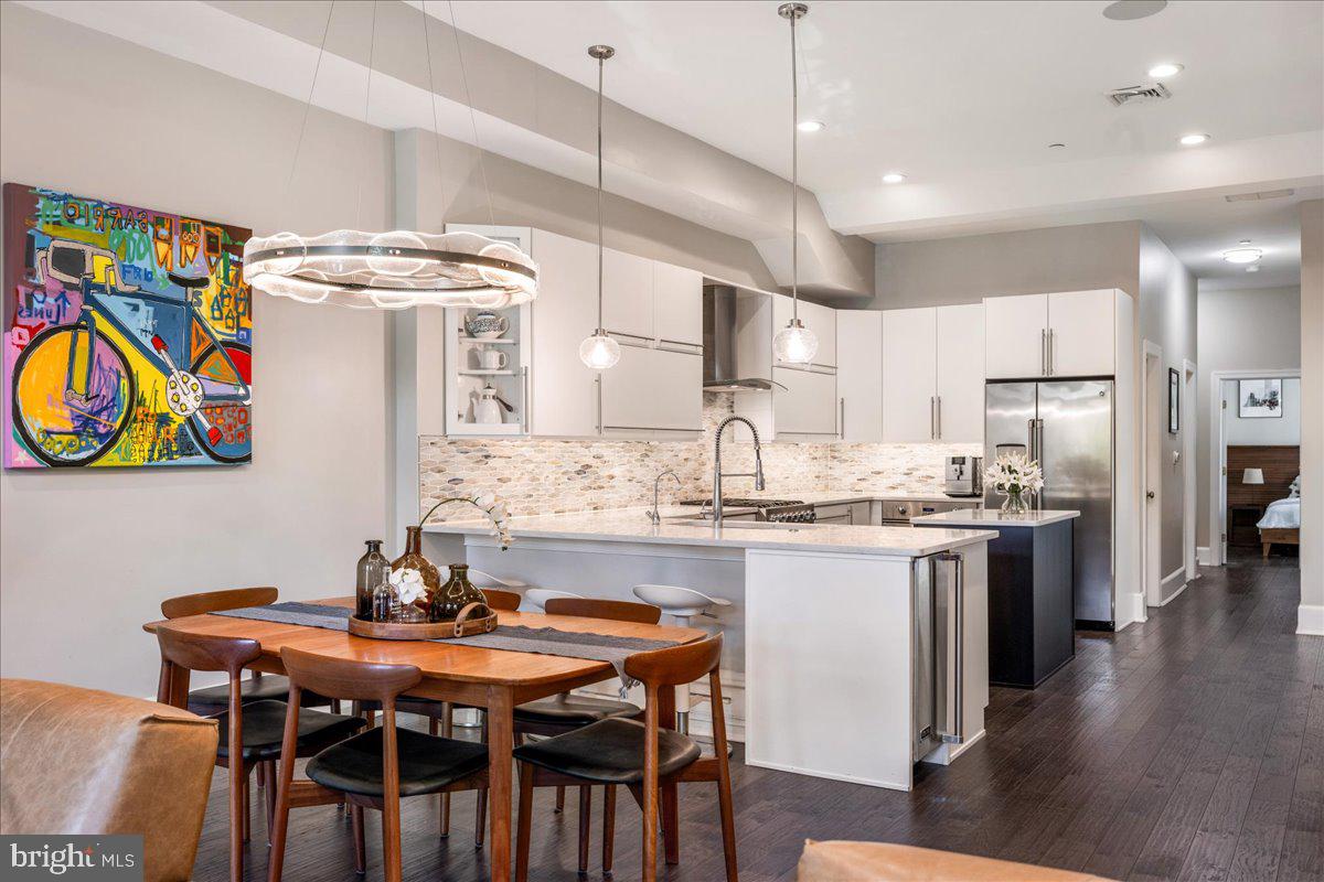 20 East Court Street Doylestown, PA 18901 - Photo 7 of 34 a kitchen with stainless steel appliances kitchen island granite countertop a table chairs in it and wooden floors