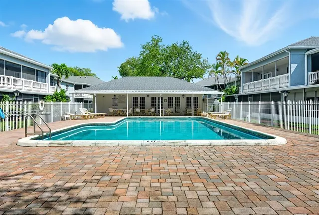 a view of swimming pool with lawn chairs and plants