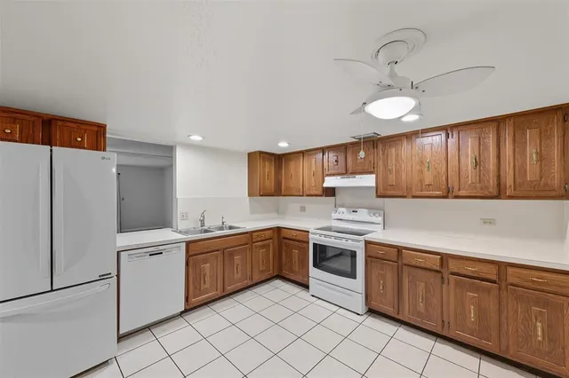 a kitchen with stainless steel appliances granite countertop a sink and dishwasher a refrigerator with wooden cabinets