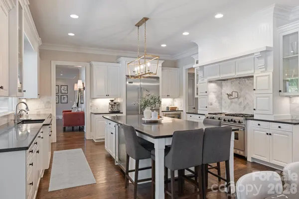 a kitchen with stainless steel appliances granite countertop a stove top oven a sink dishwasher a dining table and chairs with wooden floor