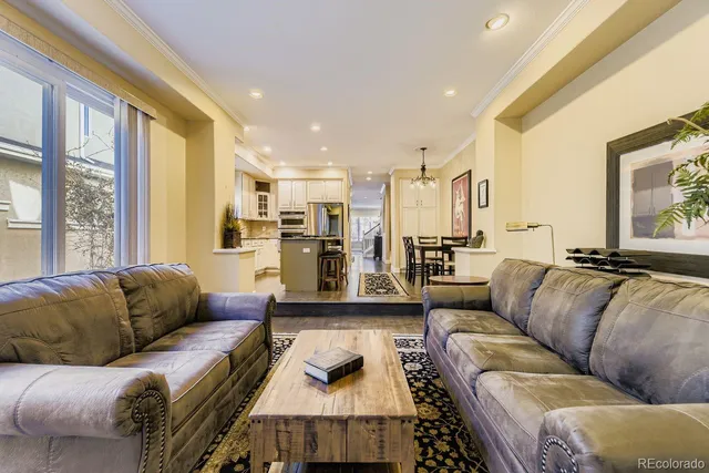 a living room with furniture wooden floor and a kitchen view