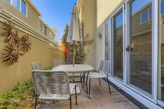 a patio with table and chairs and potted plants