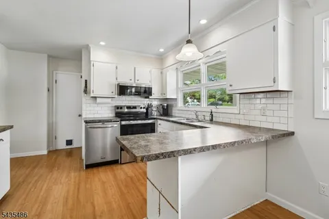 a kitchen with stainless steel appliances granite countertop a sink a stove and a wooden floors