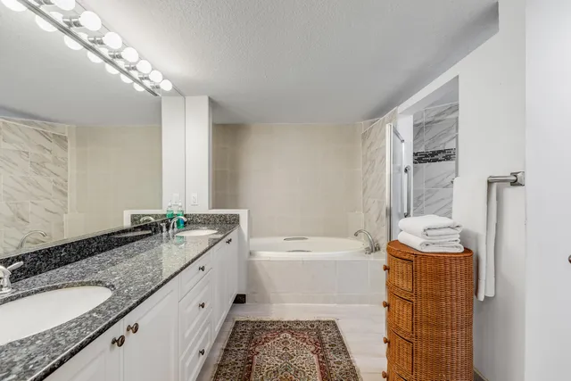 a bathroom with a granite countertop sink a toilet a mirror a vanity and shower