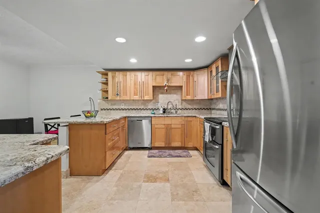 a kitchen with stainless steel appliances granite countertop a refrigerator a sink a stove and island
