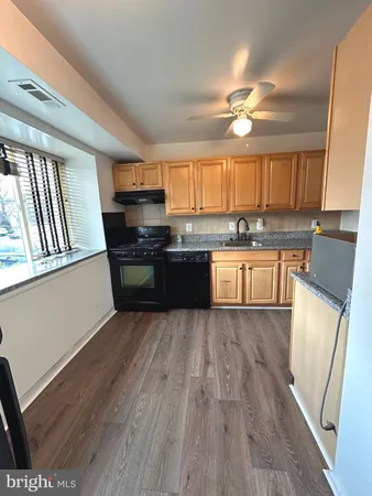 a kitchen with granite countertop wooden floors a stove and a microwave